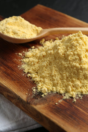 Pile of corn flour and spoon on table, closeup