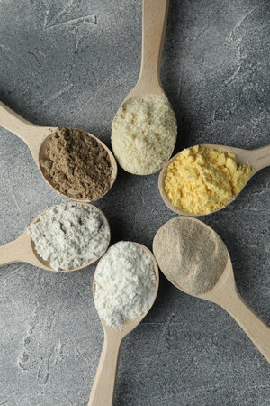 Different types of flour in spoons on grey table, flat layの写真素材