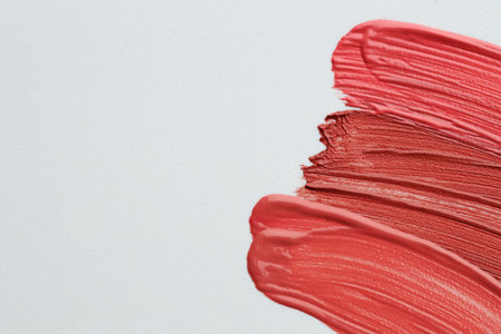 Colorful lip glosses on grey background, flat lay. Space for textの写真素材