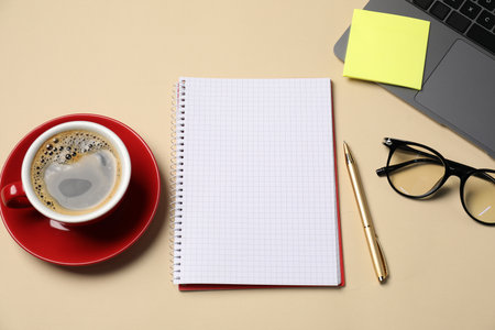 Notebook, sticky note, pen, coffee, glasses and laptop on beige background, flat layの写真素材