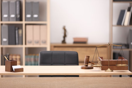 Judge's gavel, scales, stationery and document tray on table in officeの写真素材