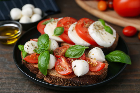 Tasty sandwiches with mozzarella cheese, tomatoes, basil and spices on wooden table, closeupの写真素材