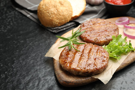 Delicious hamburger patties and spices on black table, closeup. Space for textの写真素材