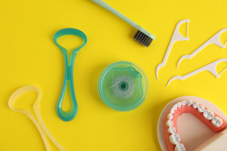 Different oral care products and dental model on yellow background, flat layの写真素材