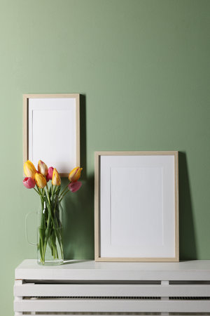 Empty picture frames and beautiful tulips indoors