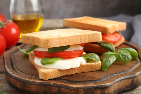 Tasty sandwiches with mozzarella cheese, tomatoes and basil on table, closeup