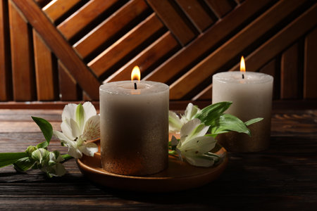 Burning candles and lily flowers on wooden table, closeupの写真素材