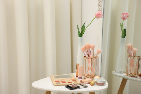 Different makeup products and brushes on white table near mirror indoors. Space for textの写真素材