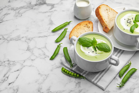 Tasty pea cream soup with basil served on white marble table. Space for textの写真素材
