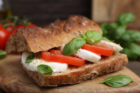 Tasty sandwich with mozzarella cheese, tomatoes and basil on wooden table, closeupの写真素材