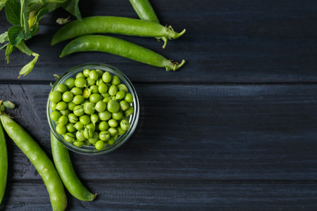 Fresh ripe green peas on black wooden table, flat lay. Space for textの写真素材