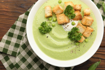 Tasty pea cream soup with croutons and broccoli served on wooden table, top viewの写真素材