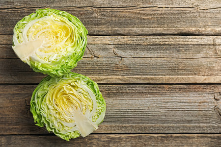 Halves of fresh cabbage on wooden table, flat lay. Space for textの写真素材