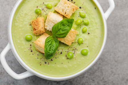 Tasty pea cream soup with croutons and basil on grey table, top viewの写真素材