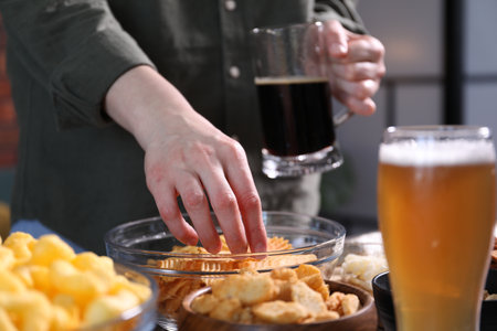 Woman with beer and chips indoors, closeupの写真素材