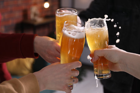 Friends clinking glasses of beer indoors, closeupの写真素材