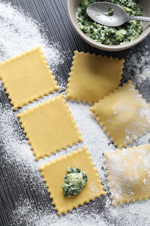Making ravioli with cottage cheese and spinach at wooden table, flat layの写真素材