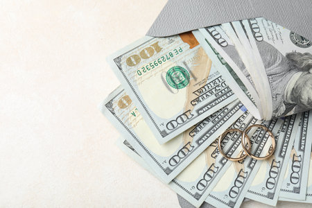 Two gold wedding rings, dollar banknotes and envelope on white table, top view. Space for textの写真素材