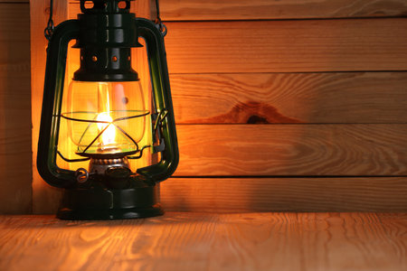 Vintage kerosene lamp on wooden table. Space for text