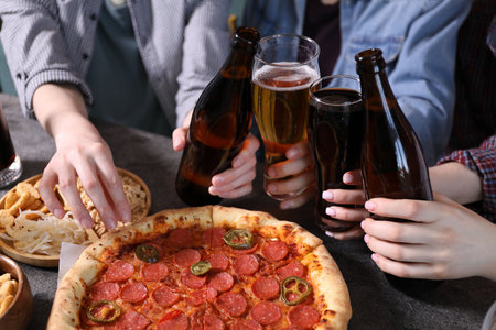 Friends with beer and snacks at gray table, closeupの写真素材