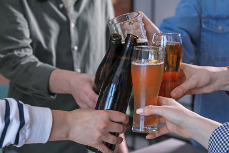 Friends clinking glasses of beer indoors, closeupの写真素材