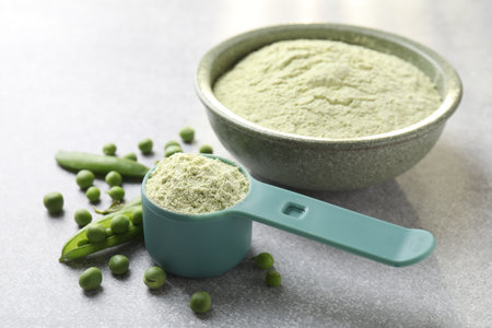Protein powder and fresh green peas on light gray table, closeupの写真素材