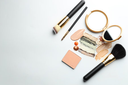 Different cosmetic products, makeup brushes and mirror on white background, flat lay. Space for textの写真素材