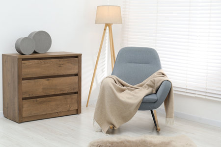 Comfortable armchair with beige woolen blanket indoors
