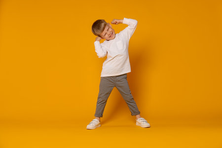 Happy little boy dancing on orange backgroundの写真素材