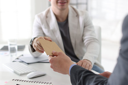 Money bonus. Employee receiving envelope from boss in office, closeupの写真素材