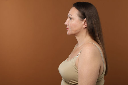 Woman before cosmetic procedure on brown background, space for textの写真素材