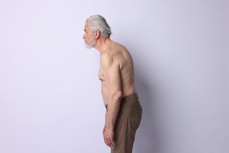 Senior man with bad posture on light backgroundの写真素材
