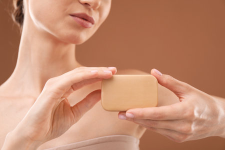Woman with soap bar on brown background, closeupの写真素材