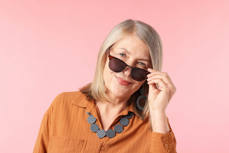 Senior woman in stylish outfit on pink background