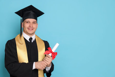Happy student with diploma after graduation on light blue background. Space for text
