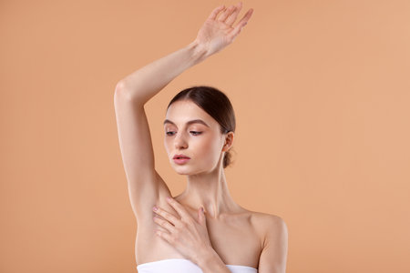 Young woman showing smooth skin after epilation on beige backgroundの写真素材