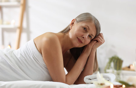 Senior woman relaxing on massage couch in spa salonの写真素材
