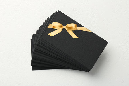 Blank gift card with golden bow on white background. Mockup for designの写真素材