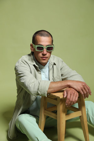 Fashionable portrait of handsome man in stylish outfit on green background