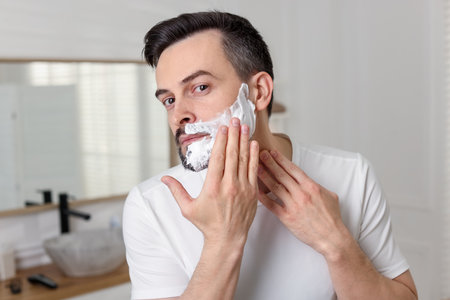 Handsome man applying shaving foam in bathroomの写真素材