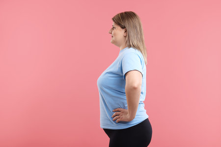 Weight loss. Plus size woman on pink backgroundの写真素材