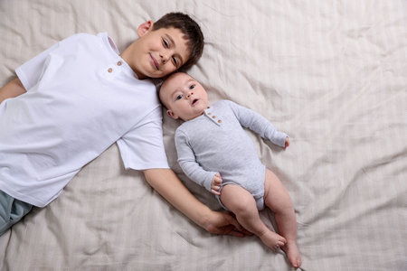 Cute little brothers on bed, top view