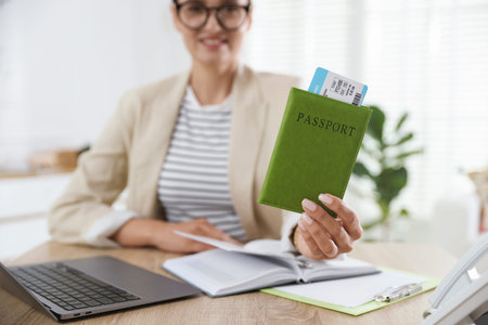 Travel agent with passport and ticket at wooden table in office, selective focus
