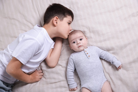 Cute little brothers on bed, top view