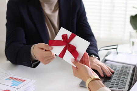 Money bonus. Employee receiving envelope with bow from boss in office, closeupの写真素材