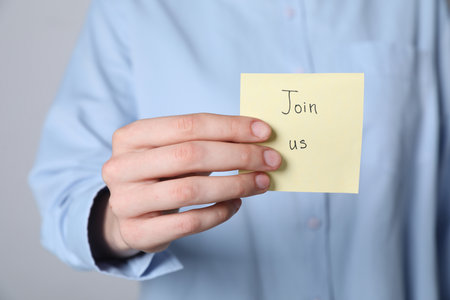 Woman holding paper note with words Join Us on gray background, closeupの写真素材