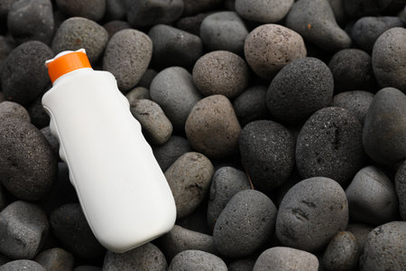 Bottle of sun protection product on pebbles, above view. Space for textの写真素材