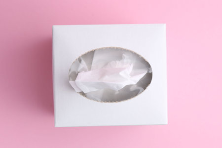 Box with paper handkerchiefs on pink background, top view