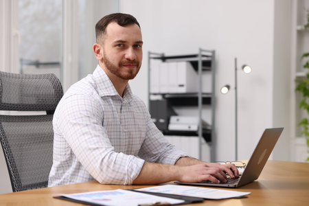 Man working on laptop at desk in officeの写真素材