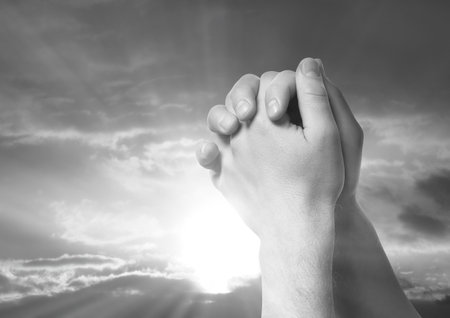 Man praying against beautiful sky with sun, closeup. Black-and-white effectの写真素材